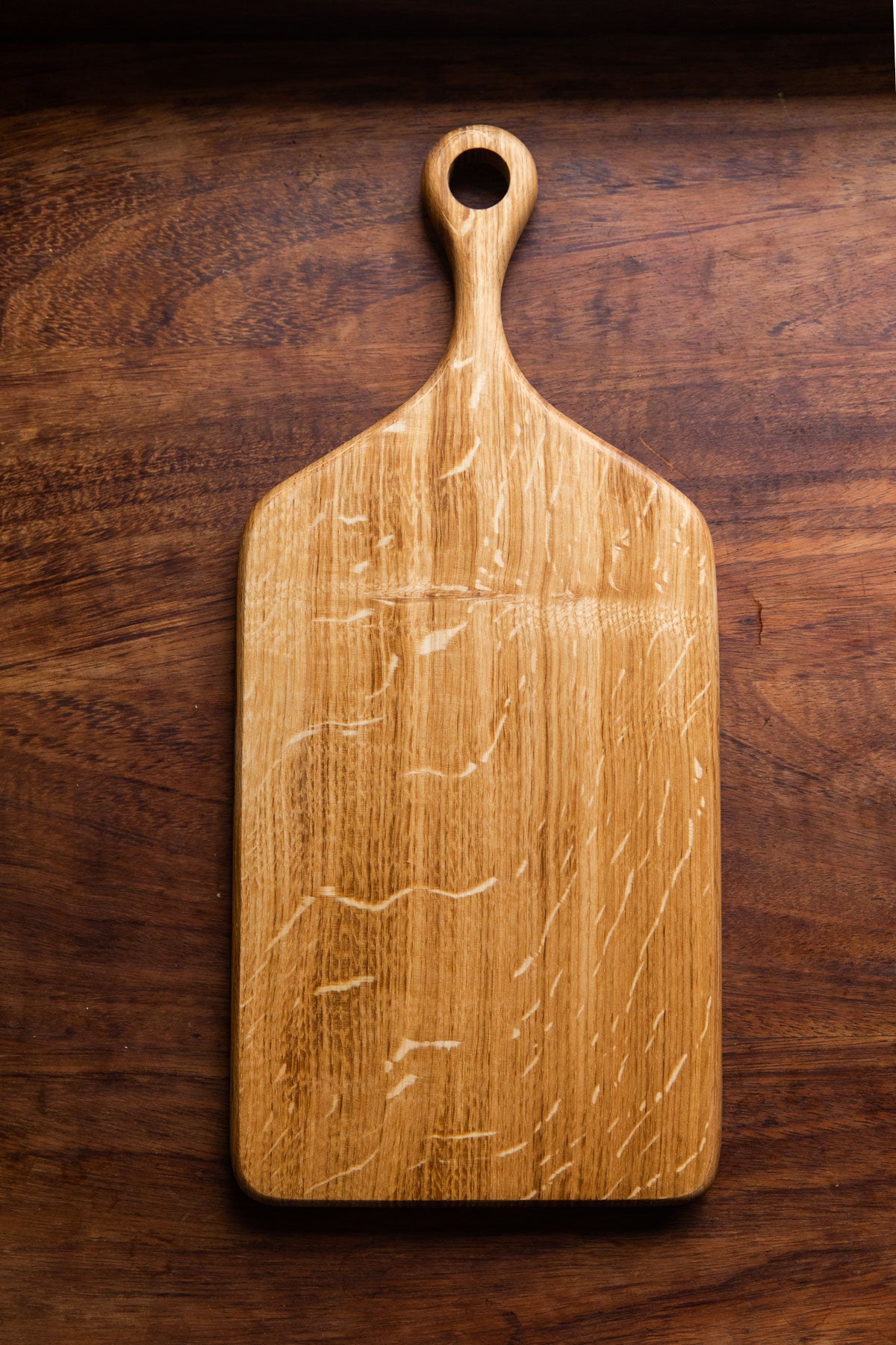 An English Oak serving board on a wooden table, taken from a birds eye view.