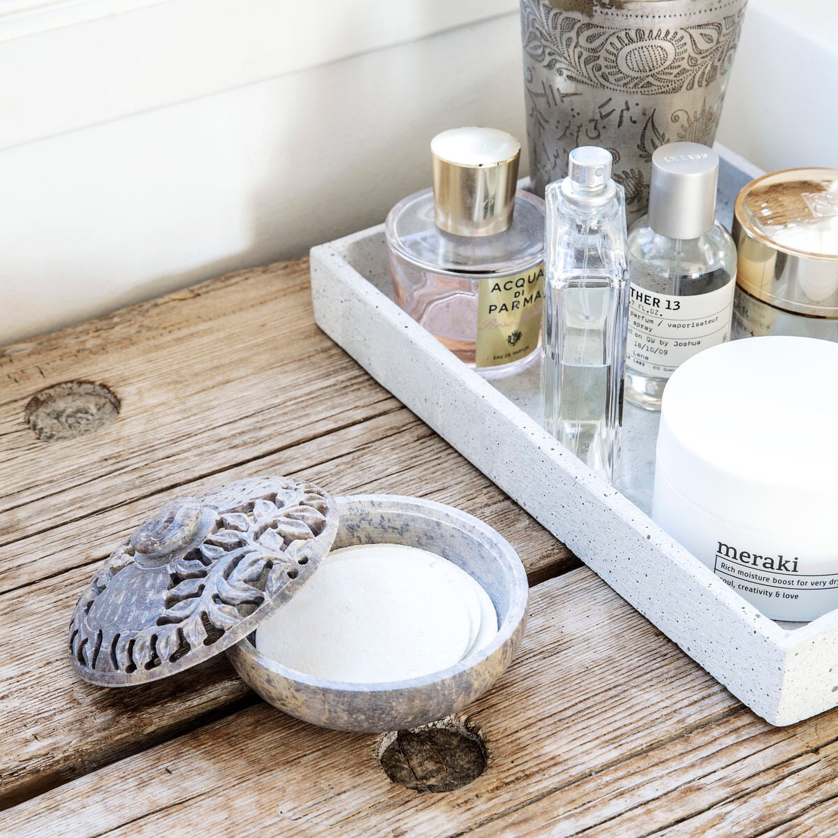 An expanded facial cleaning sponge sits on a wooden surface in a bathroom setting. 