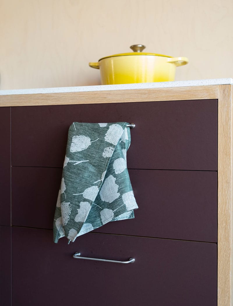 Fine Little Day's green bouquet tea towel placed in a kitchen setting.