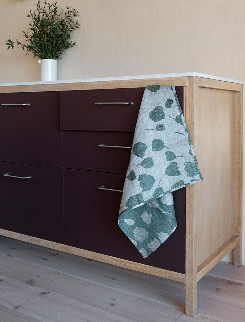 Fine Little Day's green bouquet tea towel placed in a kitchen setting.