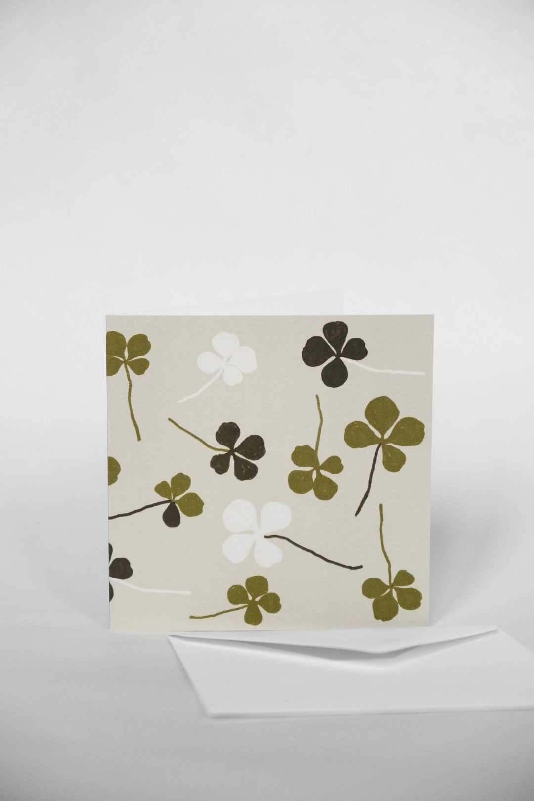 A greeting card with a four leaf clover design and green accents on a white background.