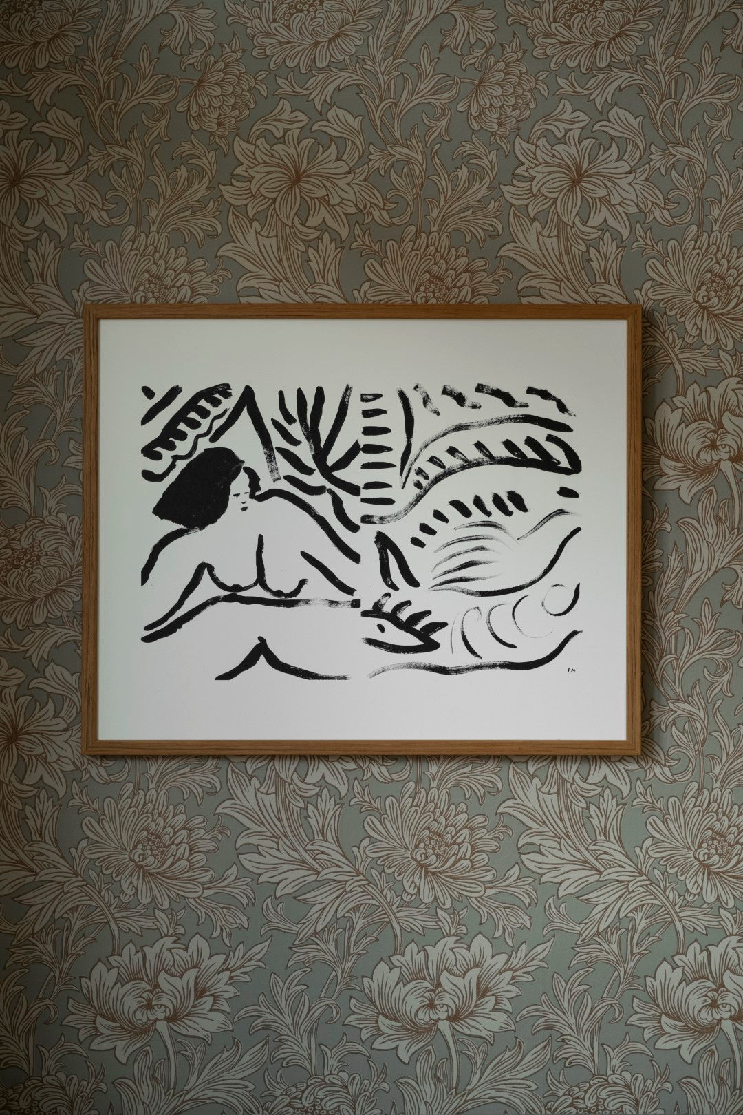 A framed poster featuring a black and white abstract artwork, hanging on a patterned wallpaper wall.