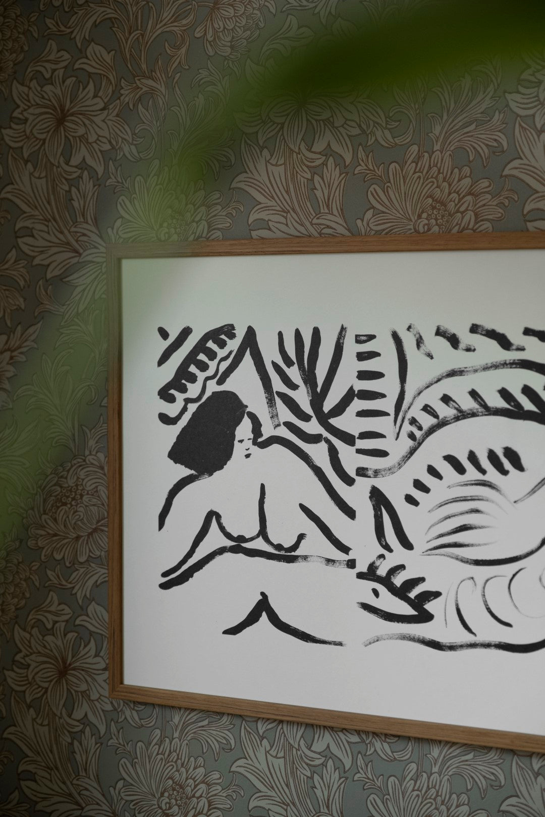 A framed poster featuring a black and white abstract artwork, hanging on a patterned wallpaper wall.