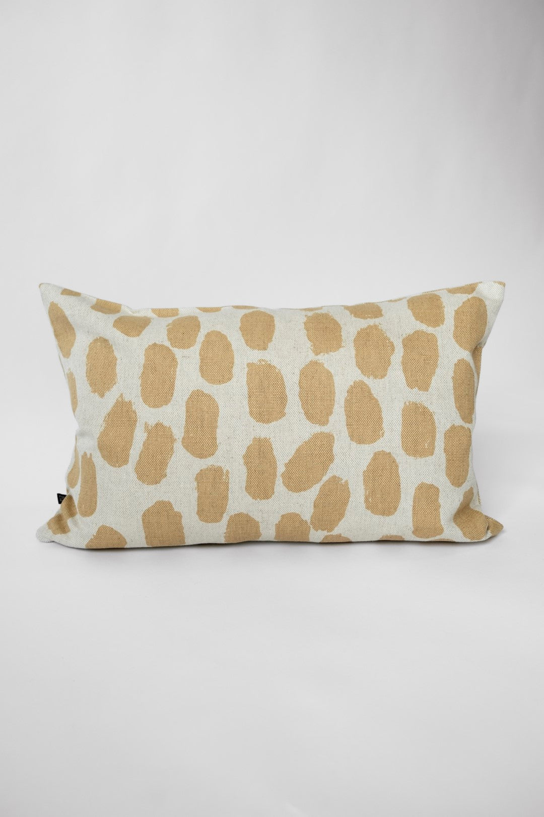 A cushion with a dotted pattern in a white and sand colourway against a white background.