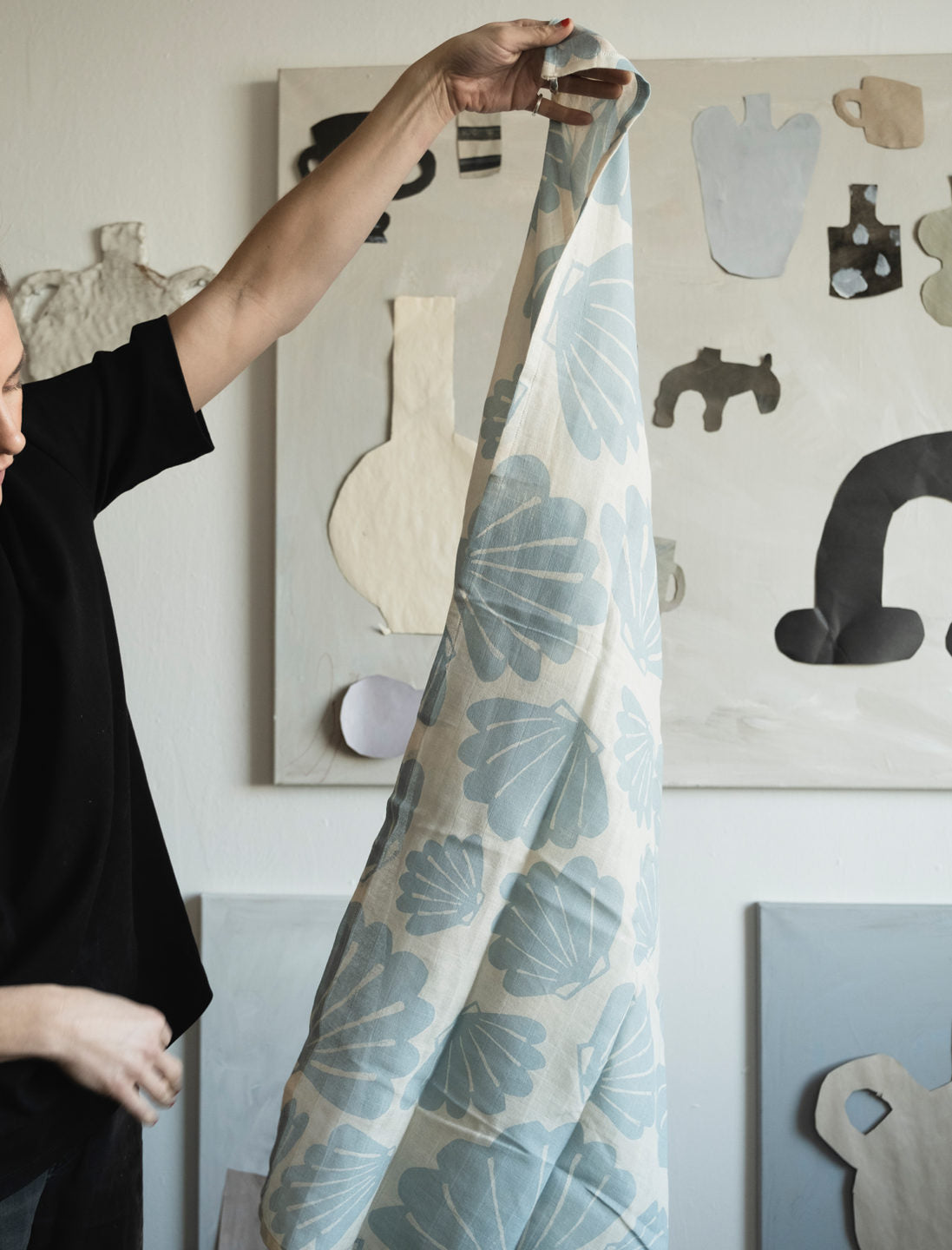 Person holding up a aqua snacka muslin from Fine Little Day in front of a paper collage in the background.