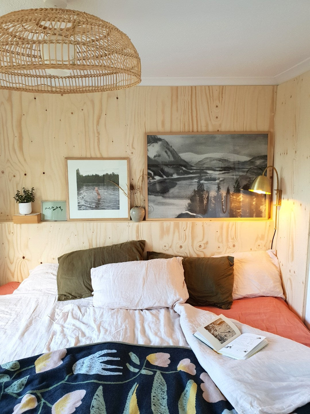 Bedroom with scattered pillows, and framed posters framed behind the bed.