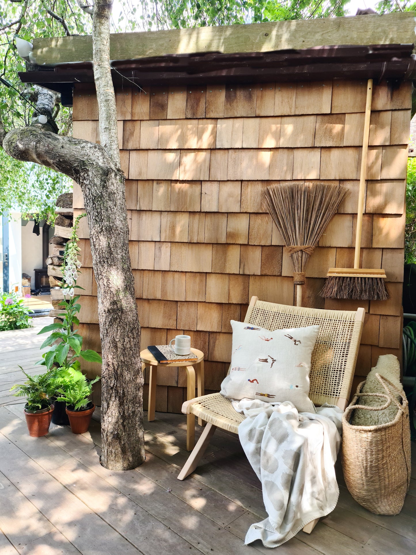 Garden scene featuring two wooden brooms and a chair draped in a blanket and cushion.