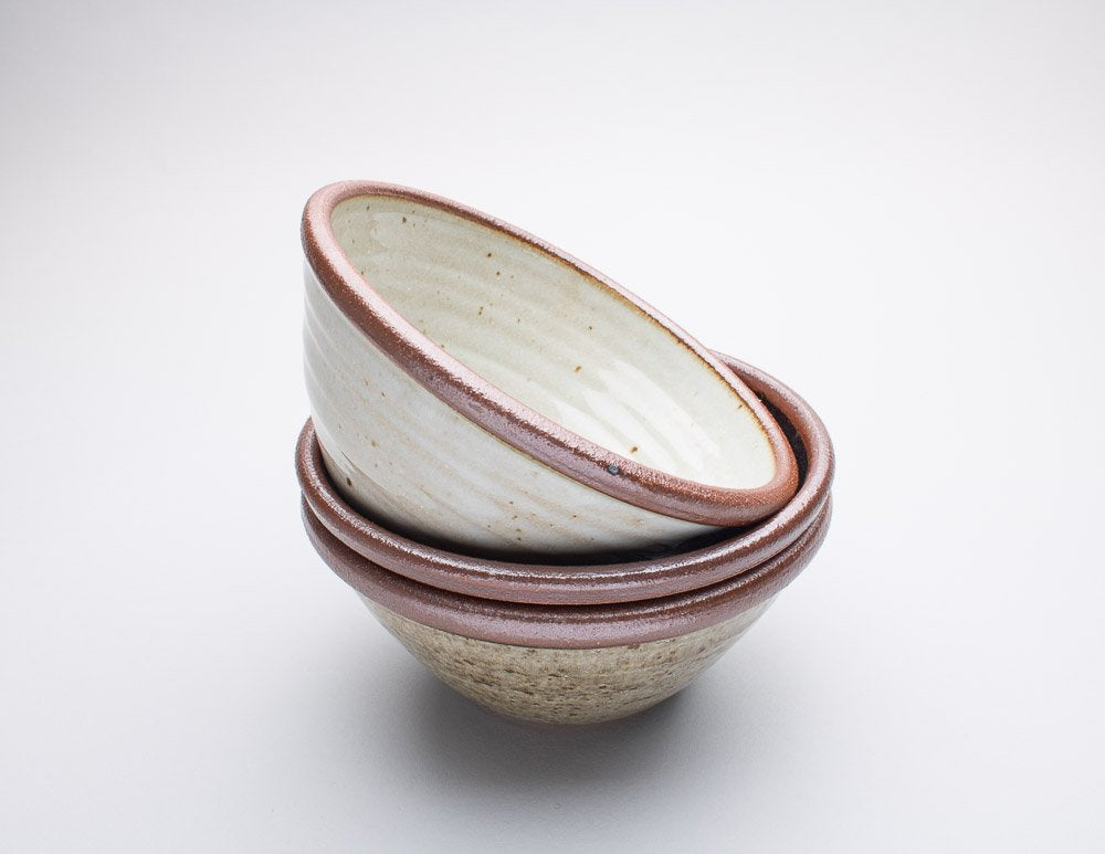 Set of three handthrown Leach Pottery bowls stacked against a white background.
