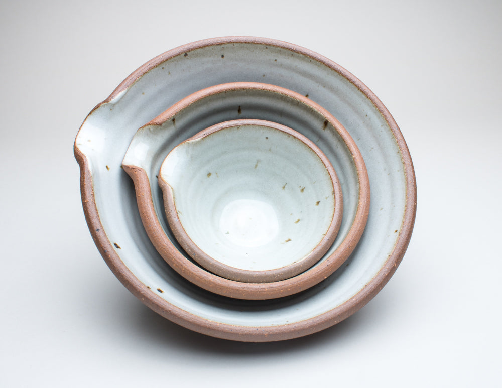 A set of three Leach Pottery mixing bowls nested inside of each other against a white background.