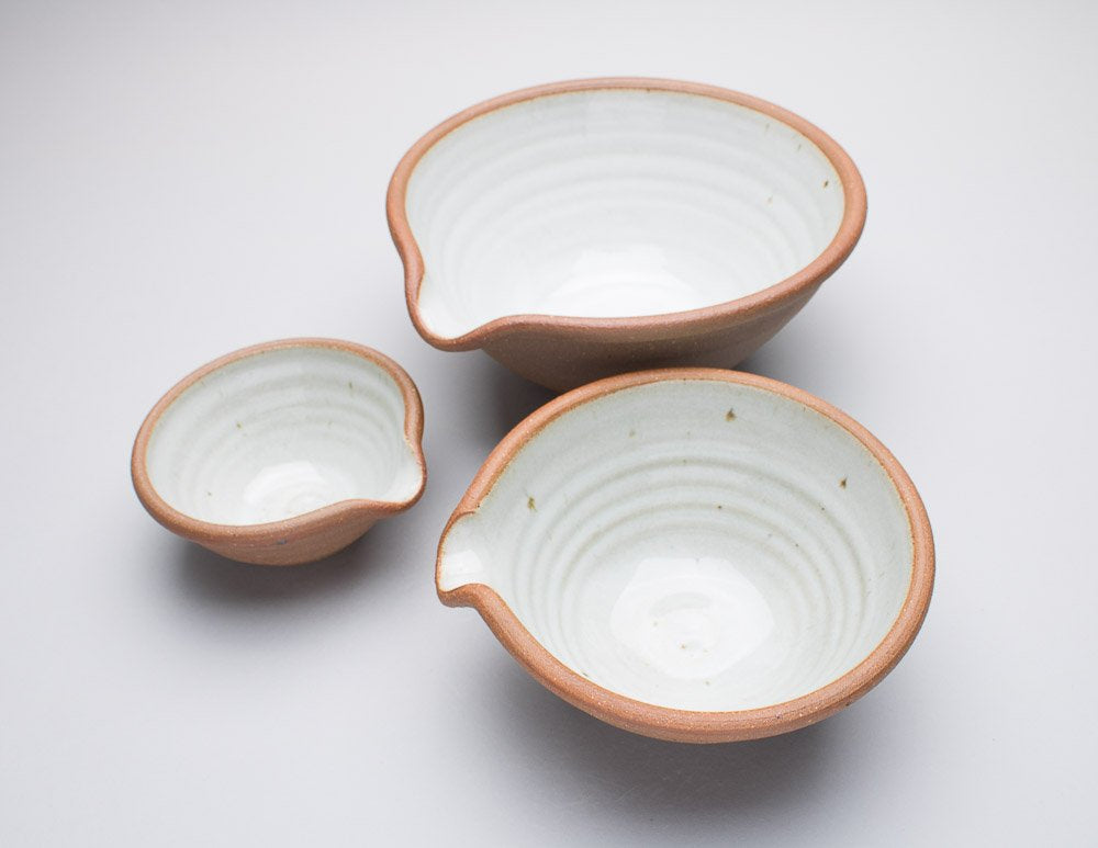 A set of three Leach Pottery mixing bowls in three different sizes against a white background.