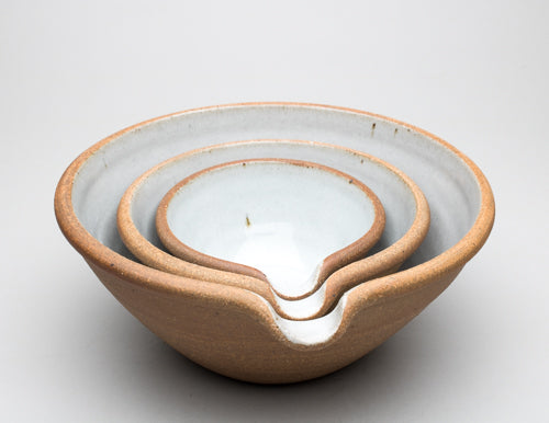 A set of three Leach Pottery mixing bowls nested inside of each other against a white background.
