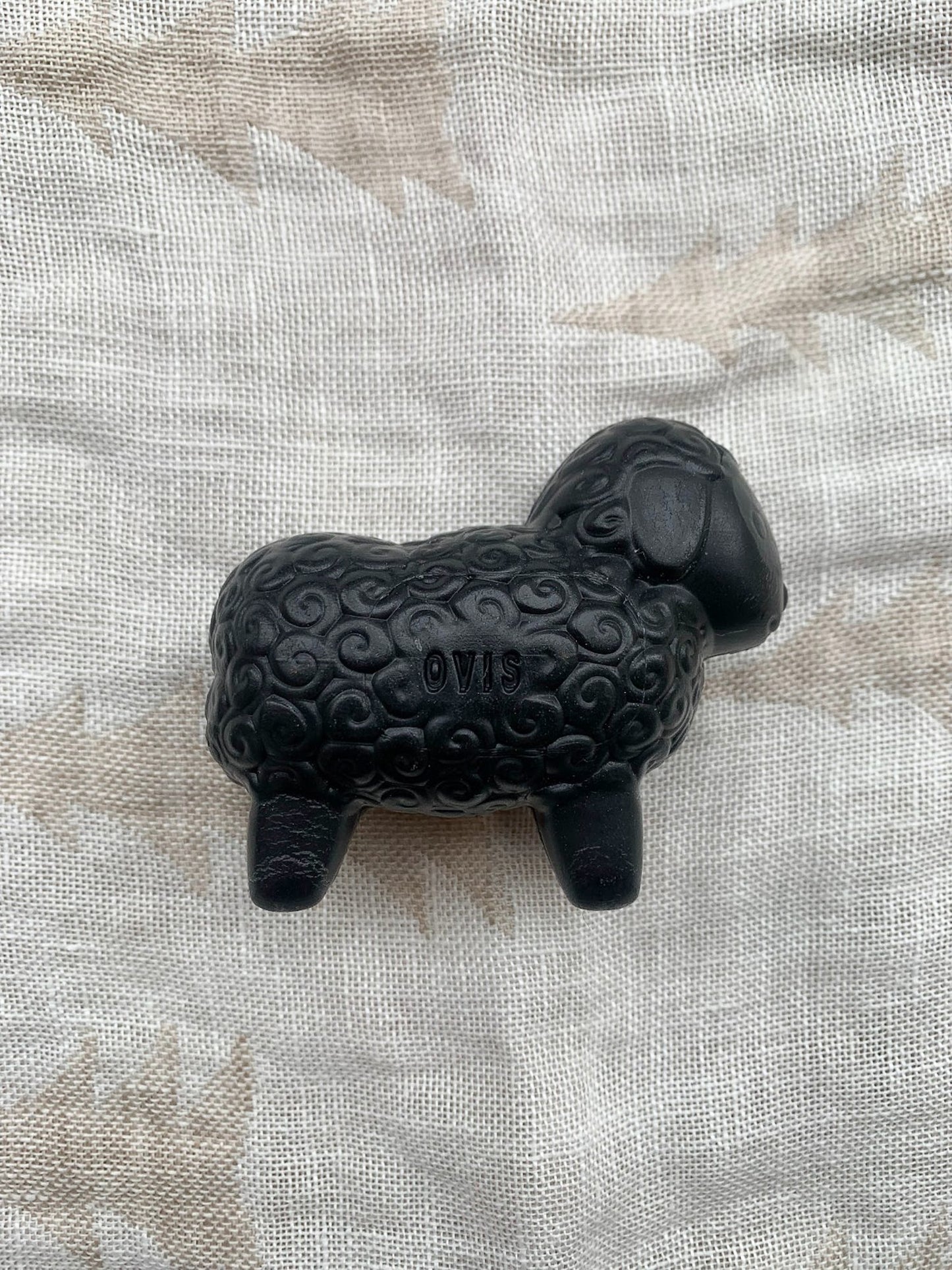 Black sheep shaped sheep soap on a textured background.