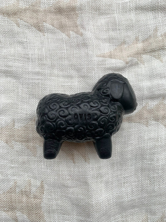 Black sheep shaped sheep soap on a textured background.