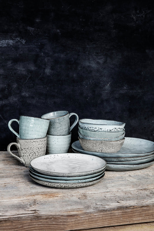 A set of ceramic cake plates with a rustic bluey/grey glaze, displayed on a wooden surface.