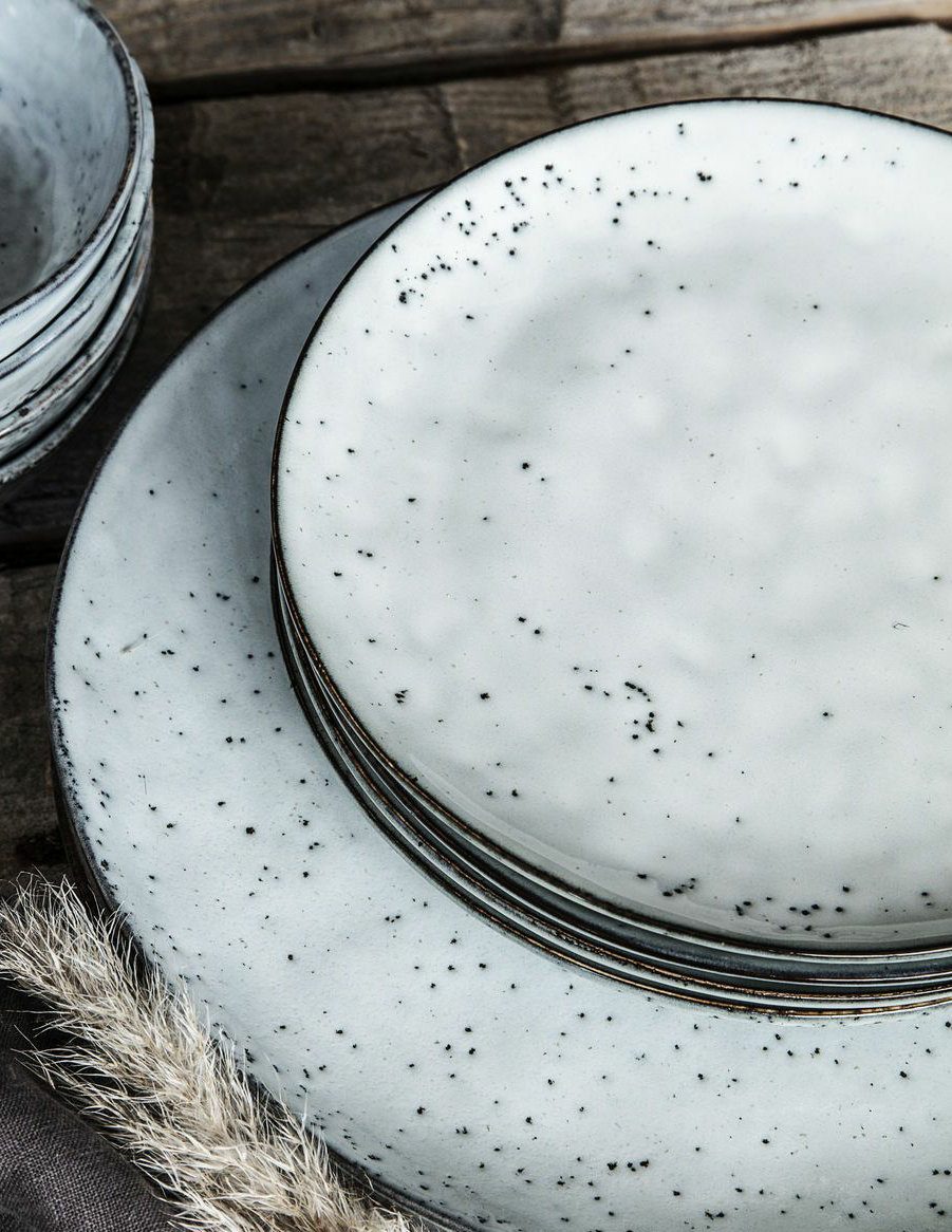 Rustic dinnerware piled on top of each other.