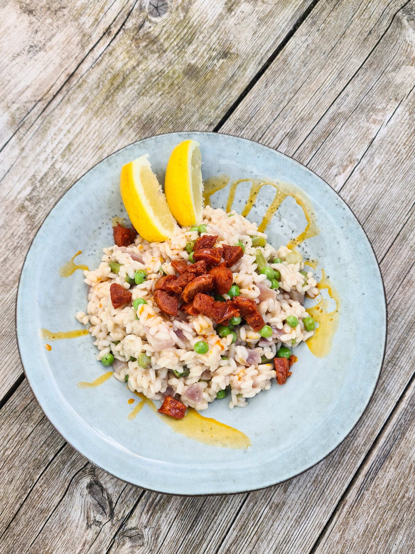 A rustic grey blue pasta bowl on wooden table filled with delicious looking food.