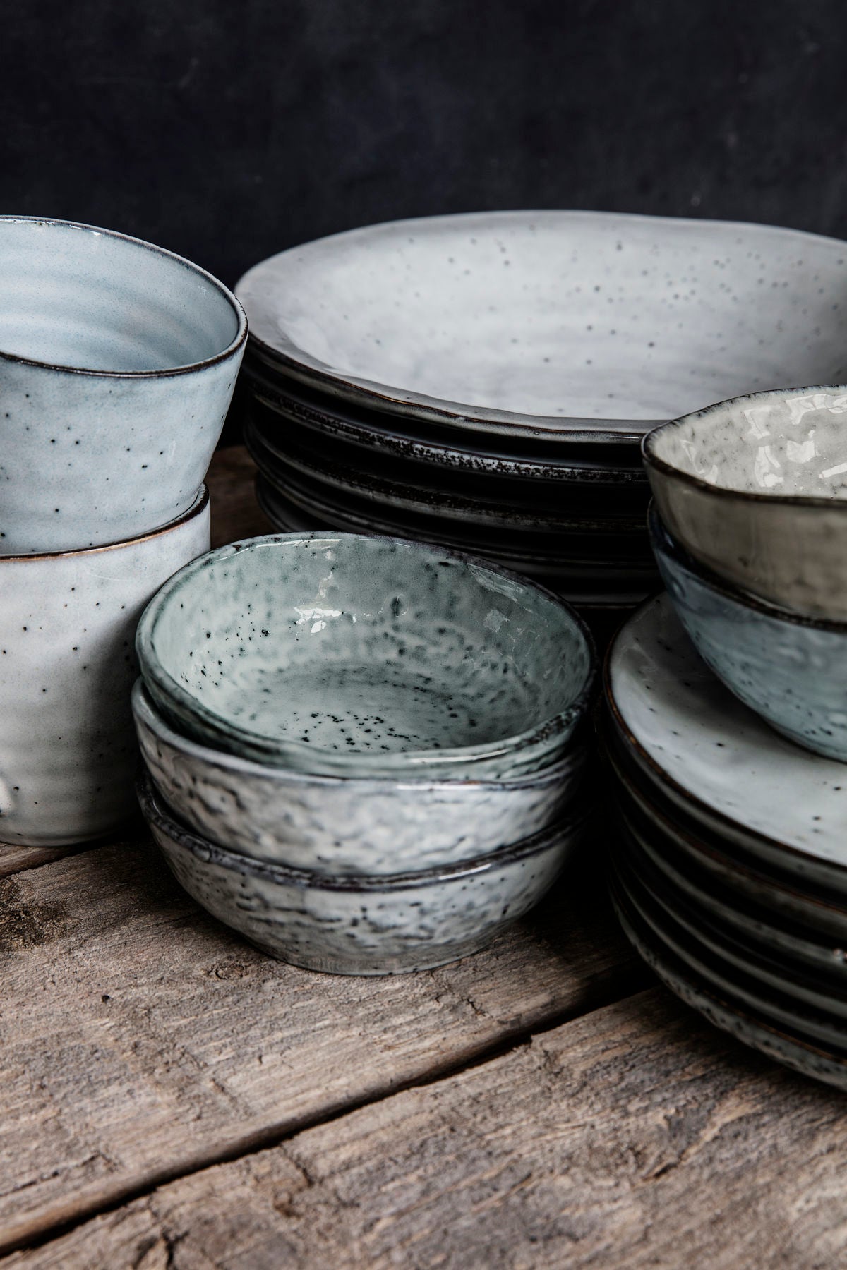 Gathering of rustic dinnerware pieces on a wooden table.