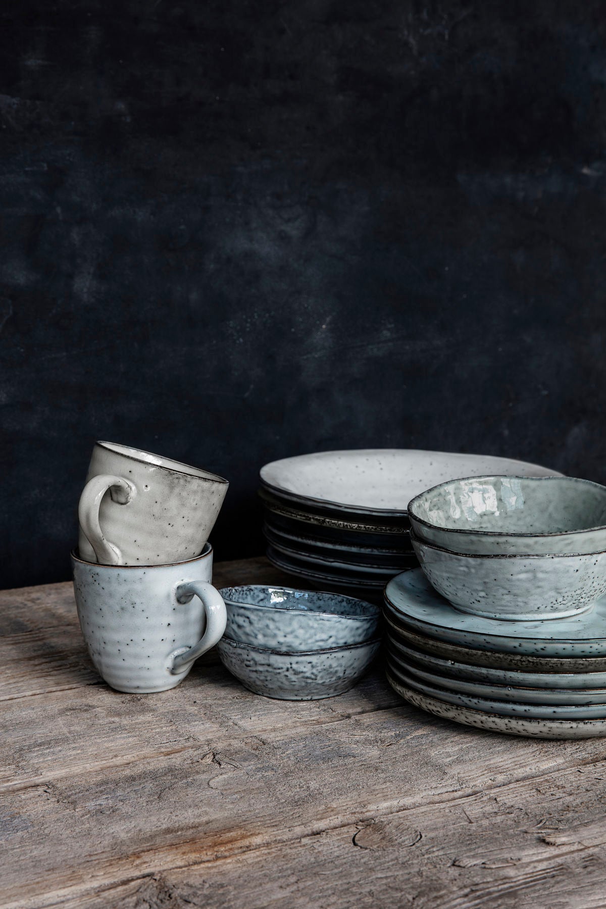 Gathering of rustic dinnerware pieces on a wooden table.